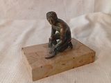 statue représentant un homme assis sur un bloc, un couteau à la main