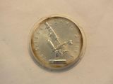 a silver coin with a microscope on it on a white surface