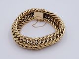 a close up of a gold chain bracelet on a white surface