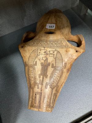 un vieux vase en bois orné d'un motif, exposé dans une vitrine