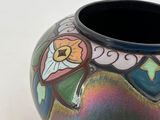 a vase with a colorful design on it on a white surface