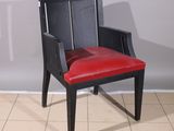 a black chair with a red leather seat on a tile floor