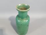 a small green vase sitting on a white surface
