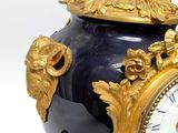 a blue and gold vase with a clock on it