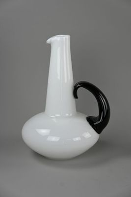 Pichet en verre teinté blanc avec anse noire.