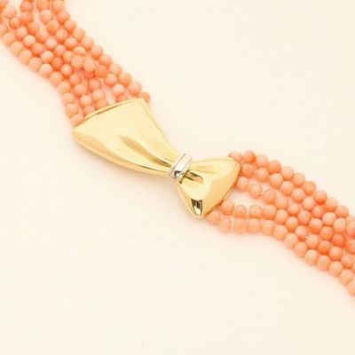 a close up of a necklace on a white surface with a gold clasp