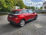 a red car parked in a parking lot with trees in the background