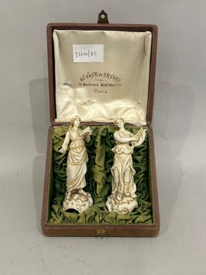 two figurines in a box on a table with a white cloth