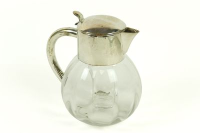 un pichet en verre muni d'une anse en métal, sur fond blanc