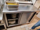 une femme debout dans une cuisine, avec une casserole remplie de nourriture posée sur le plan de travail