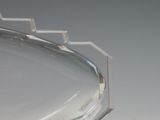 a silver plate with a curved edge on a white surface