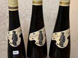 three bottles of wine sitting on top of a wooden barrel