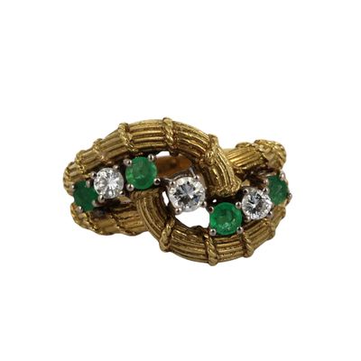 gros plan d'une bague en or avec des pierres vertes et blanches