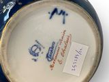 a blue and white vase that has a tag on it