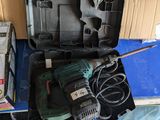 une boîte contenant une perceuse et d'autres outils, posée par terre