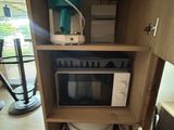 a microwave sitting inside of a cabinet with a trash can