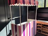 a pink and white striped food cart in the middle of a room