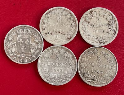 quatre pièces d'argent de tailles et de formes différentes sur un fond rouge