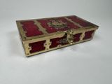 une boîte ancienne en laiton et rouge, ornée d'un lion sur le couvercle