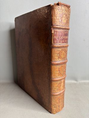 un vieux livre posé sur une table à côté d'un mur
