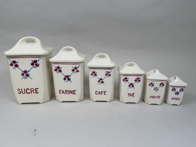 four white canisters with red flowers on them sitting on a white surface