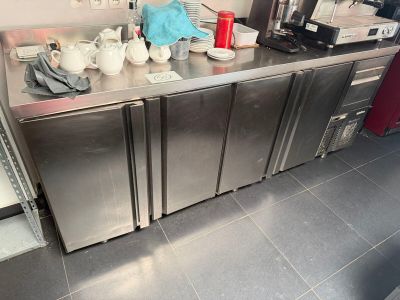 a stainless steel counter in a commercial kitchen with teapots and cups on it