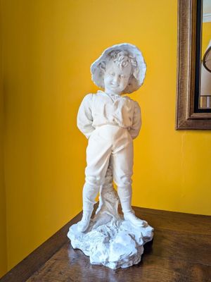 a statue of a boy standing on a table in front of a mirror