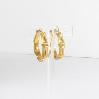Les boucles d'oreilles en bambou doré sont exposées sur un fond blanc