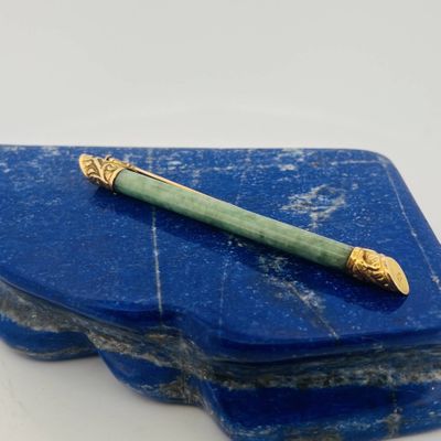 blue stone with a green pen on top of it on a white surface