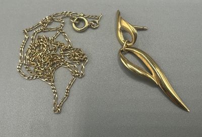 Deux bijoux sont posés sur une table, à côté d'une paire de ciseaux.