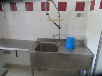 a sink in a kitchen with a blue bucket on the counter