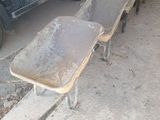 several wheelbarrows are lined up in a garage with a truck in the background