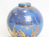 a blue vase with gold designs on it on a white surface