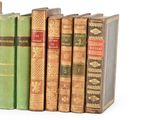 several old books are lined up in a row on a white surface