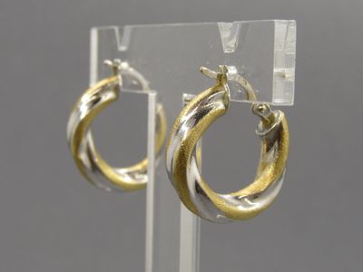 boucles d'oreilles créoles bicolores or et argent, présentées sur un présentoir transparent