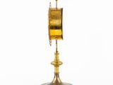 a gold clock on a stand on a white background