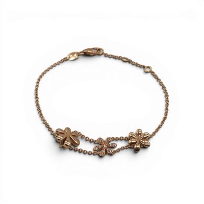 un bracelet en or avec une breloque en forme de fleur suspendue à une chaîne