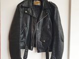 une veste en cuir noir accrochée à un mur blanc dans une pièce