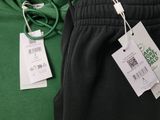 a green hoodie and black pants with a price tag on it