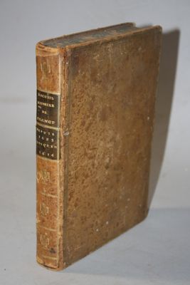 an old book sitting on top of a white table next to a white wall