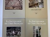 quatre livres posés sur une table blanche, contenant des illustrations de bâtiments