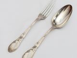 deux cuillères et une fourchette en argent sur une surface blanche