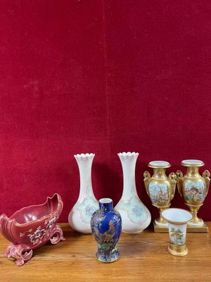 de nombreux vases et tasses posés sur une table, avec un mur rouge en arrière-plan