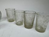 five glasses and a vase sitting on a table