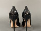 black high heeled shoes on a grey surface with a white background