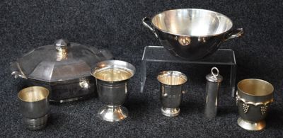 une assiette en argent et des tasses en argent posées sur un fond noir