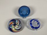 three glass vases are sitting on a white surface, one is blue and the other is red and white
