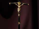 un crucifix posé sur une table recouverte d'un tissu violet