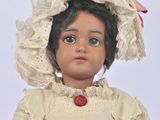 a small doll that is wearing a dress and a hat