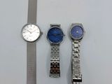 Trois montres sont posées les unes à côté des autres sur une table.